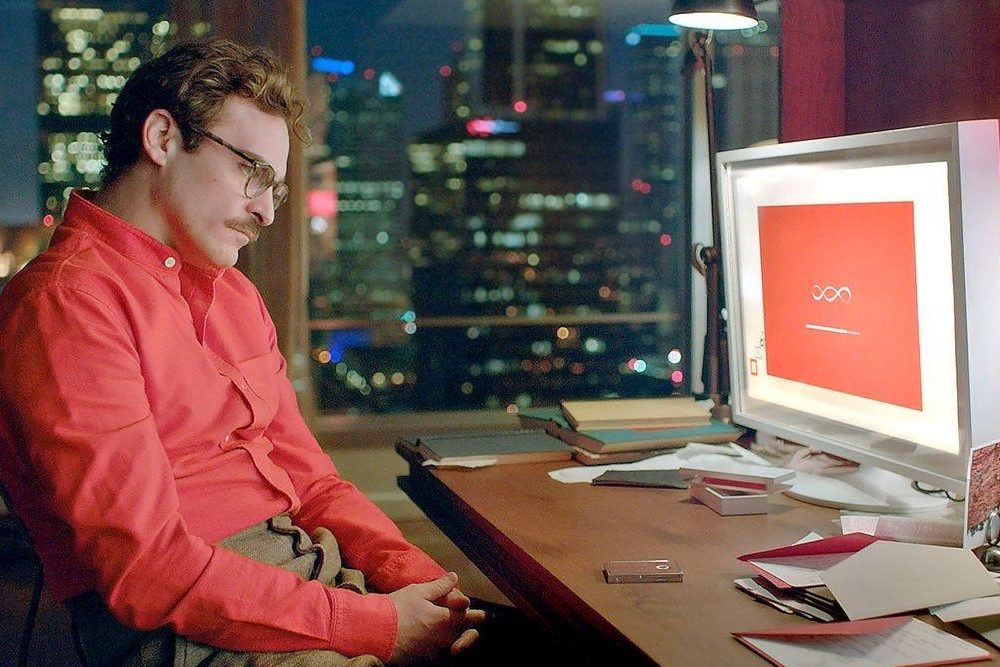 Imagem do filme Her em que vemos o personagem principal, representado por Joaquin Phoenix, a olhar para o ecrã do computador onde habitualmente corre o seu assistente pessoal com a voz de Scarlett Johansson com um ar desanimado.