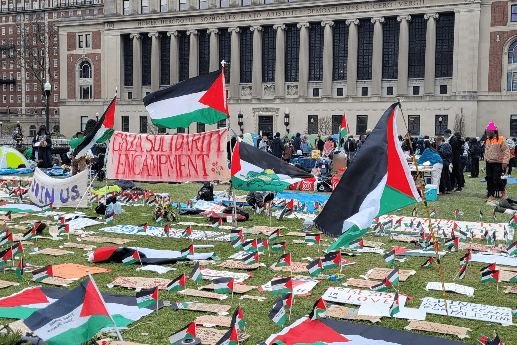 Acampamento na Universidade de Columbia com bandeiras da Palestina e cartazes